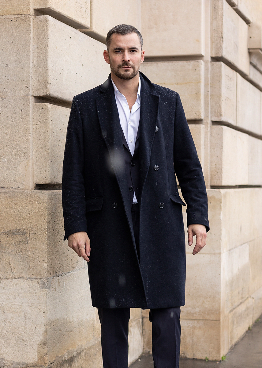 Creator Julien Man in a black coat and suit in a winter city outside