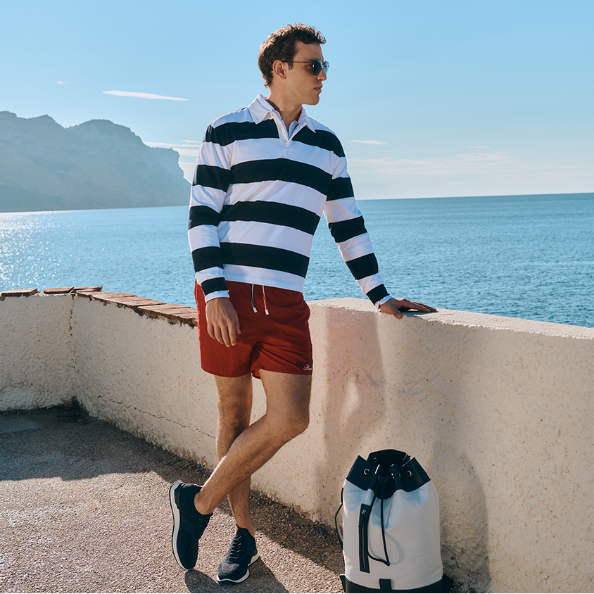 Sporty navy look Man at the quay wall in red swim trunks and striped longsleeve poloshirt