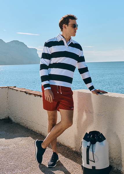 Sporty navy look Man at the quay wall in red swim trunks and striped longsleeve poloshirt