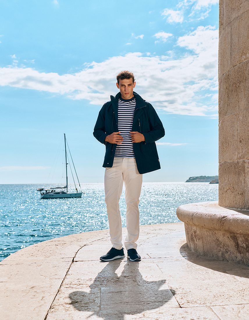 Marine Style Mann in heller Hose, mit Ringel-T-Shirt und blauer Windjacke